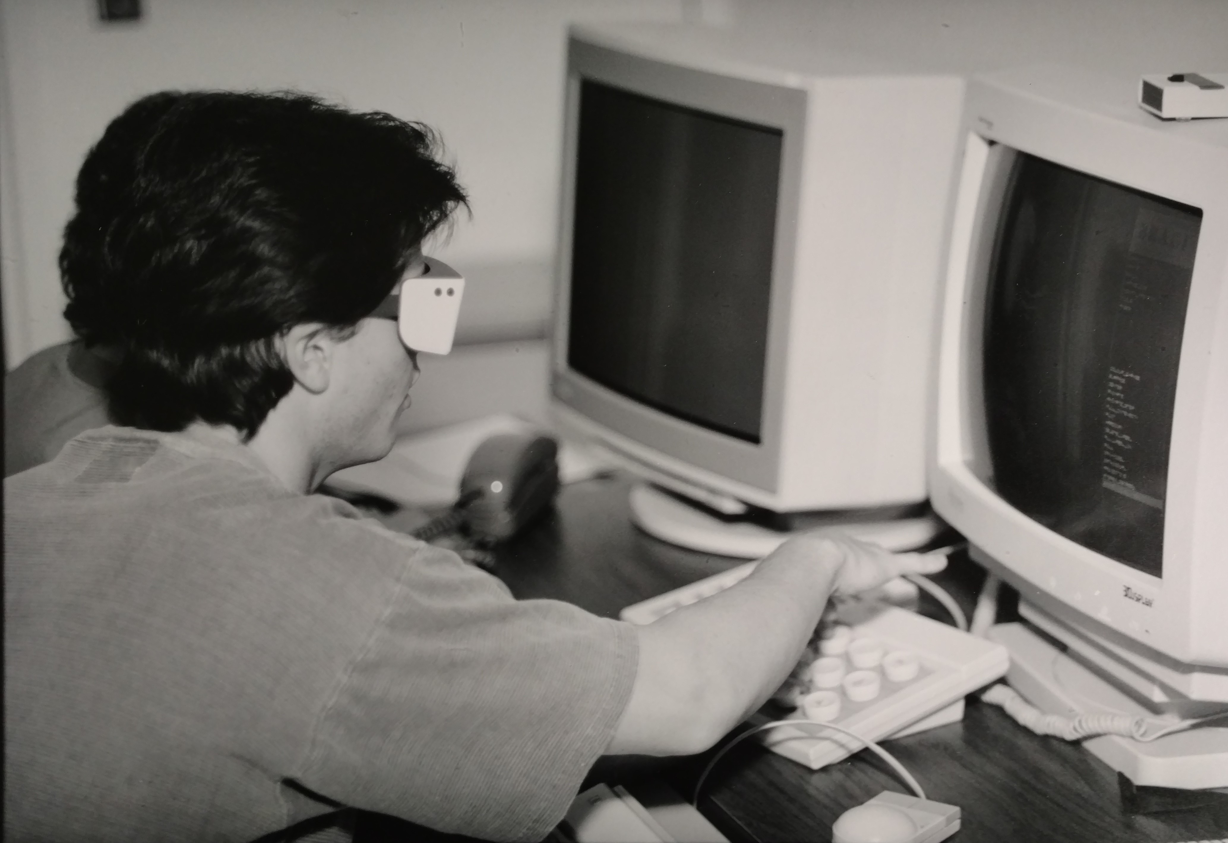 A person wearing goggles while working on a very old computer 